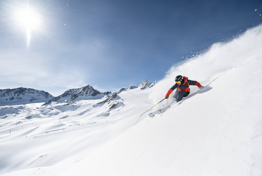 Skifahrer im Powder mit Blick aufs Skigebiet