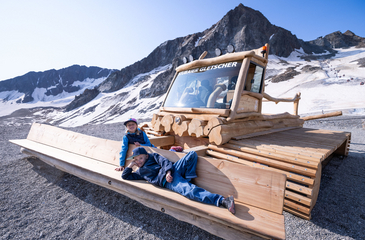 2 Kinder auf der Pistenraupe aus Holz am Höhenspielplatz Stubaier Gletscher