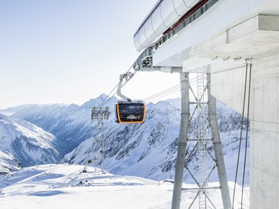 Blick ins verschneite Tal von Eisgrat Bergstation, im Vordergrund eine schwarz-orange Gondel
